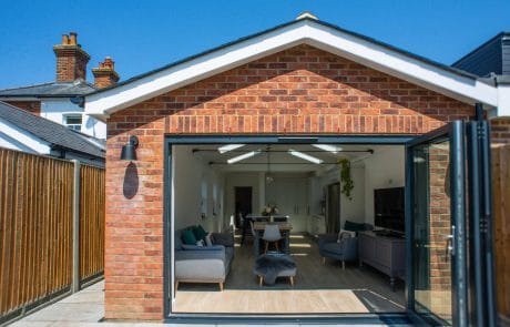 Looking though large and open glass door into living area of brick house
